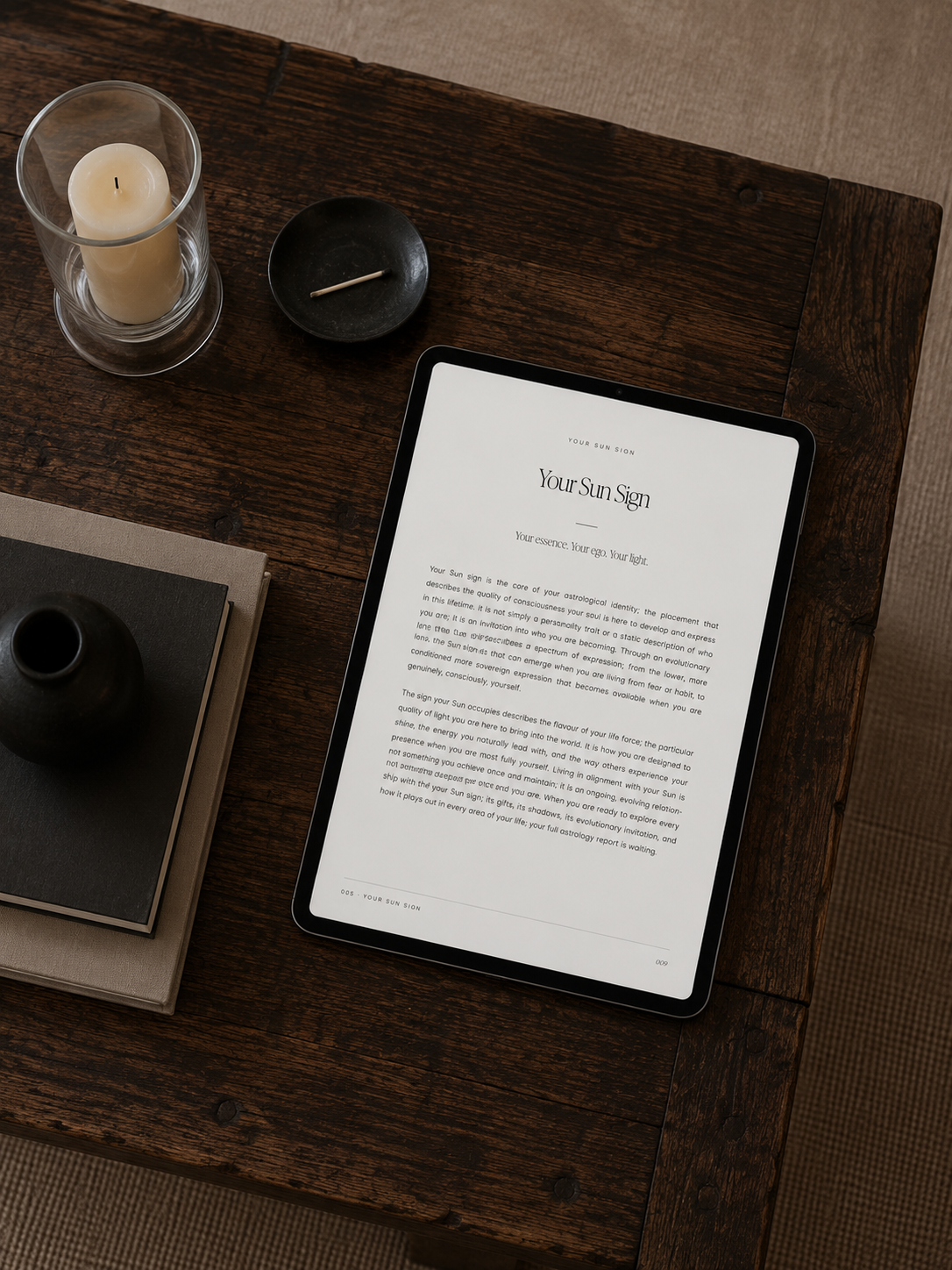 Tablet showing an astrology guide page on a dark wooden table with a candle